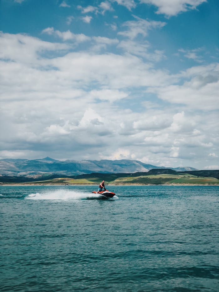 services-02 A man enjoys riding a jetski on the expansive waters of Adıyaman, Turkey, with scenic mountains in the background.
