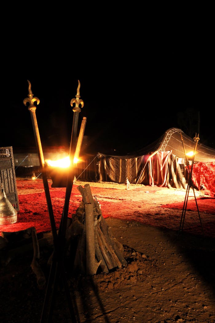 our-story Traditional Berber tent setup at night in Ouarzazate, Morocco, illuminated by torches.